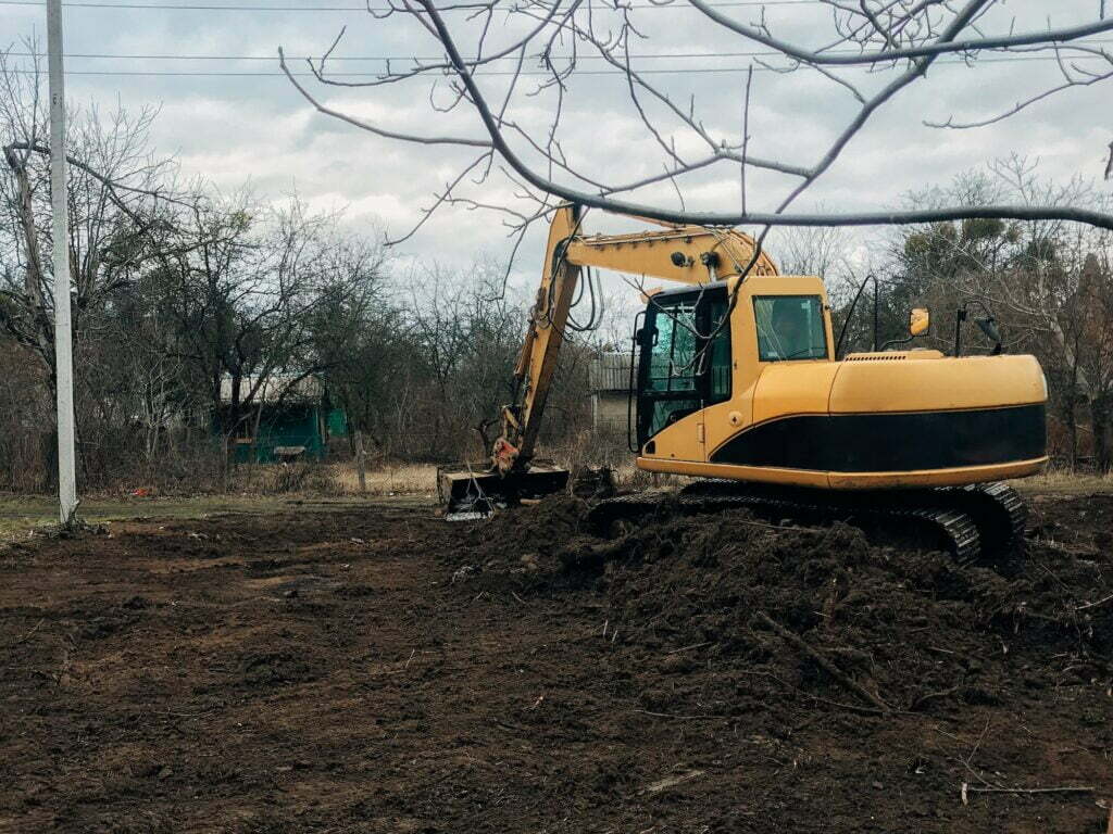 Bulldozer clearing land from old trees, roots and branches with dirt and trash